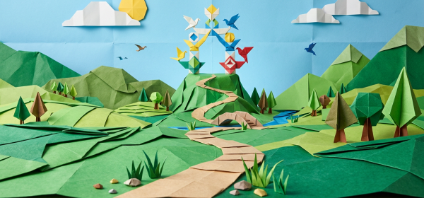 Origami landscape of green hills, trees, winding path, origami birds, sun, and clouds