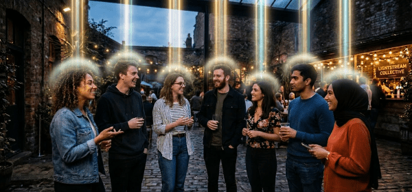 Group of seven young adults chatting and holding drinks in a cobblestone courtyard with string lights and plants.